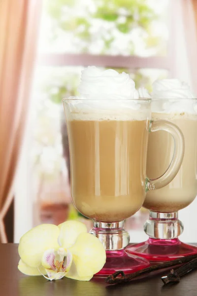 Fragrant coffee latte in glasses cups with vanilla pods, on table in cafe — Stock Photo, Image