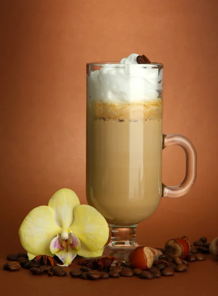 Fragrant coffee latte in glass cup with spices, on brown background — Stock Photo, Image