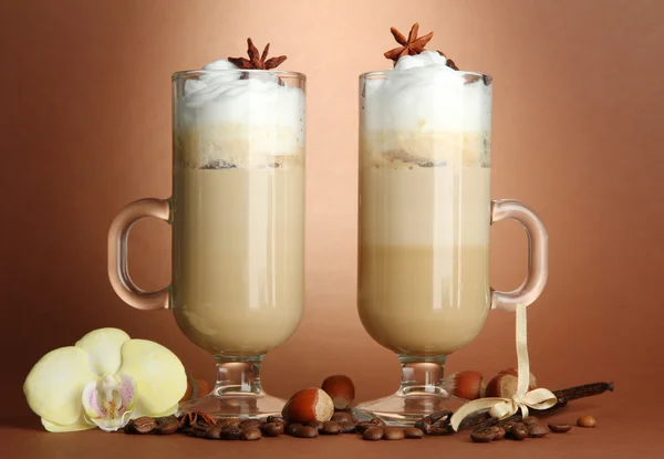 Café con leche fragante en vasos con especias, sobre fondo marrón —  Fotos de Stock