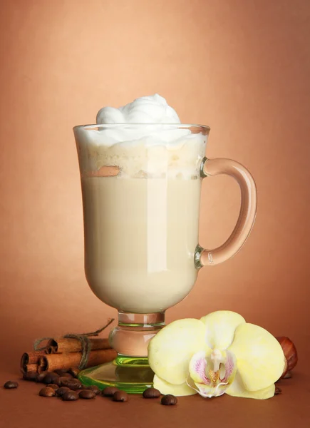 Café con leche fragante en taza de vidrio con especias, sobre fondo marrón —  Fotos de Stock