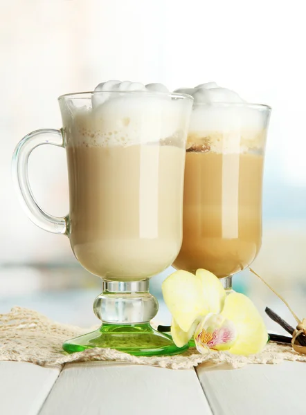Geurende koffie latte in glazen bekers met kruiden, op houten tafel — Stockfoto