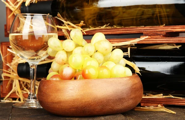 Wooden case with wine bottles, wineglass and grape close up — Stock Photo, Image