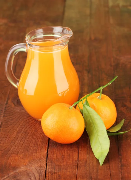 Jarro cheio de suco de tangerina, em fundo de madeira — Fotografia de Stock