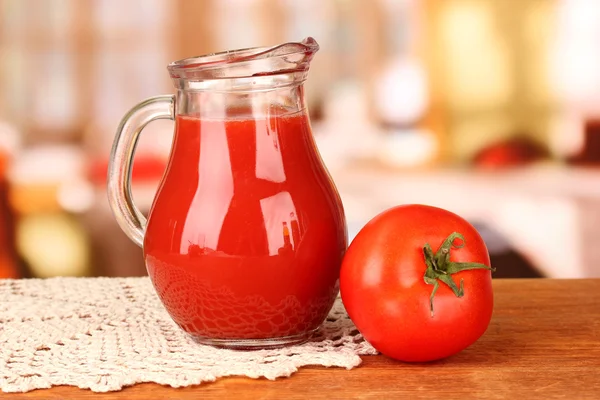 Pełny dzbanek soku pomidorowego, na drewnianym stole na jasnym tle — Zdjęcie stockowe