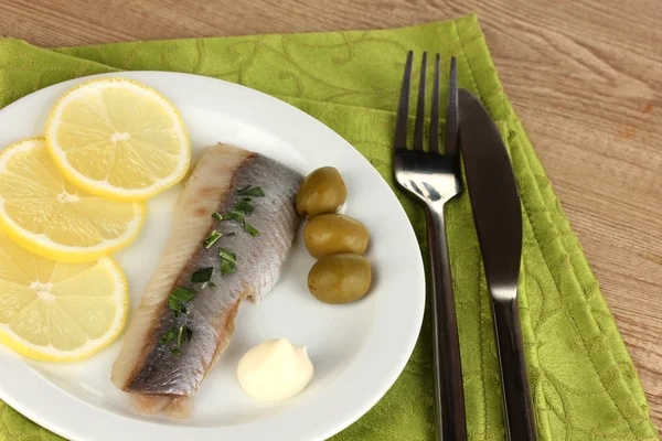 Plato de arenque y limón en plato sobre mesa de madera primer plano — Foto de Stock