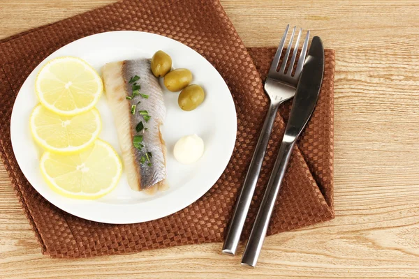 Dish of herring and lemon on plate on wooden table close-up — Stock Photo, Image