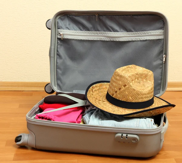 Open silver suitcase with clothing in room — Stock Photo, Image