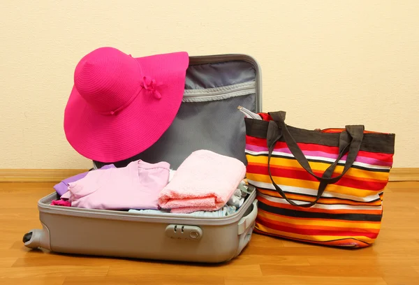 Open silver suitcase with clothing in room — Stock Photo, Image