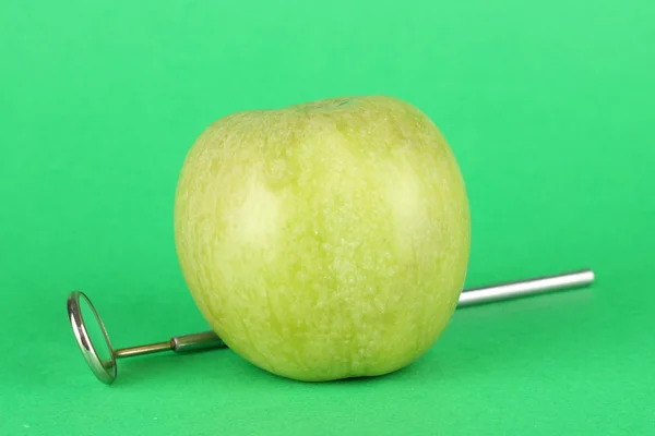 Groene appel en tandheelkundige tool op kleur achtergrond — Stockfoto