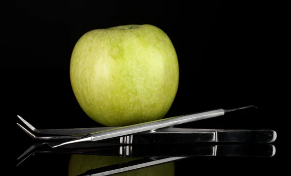 Groene appel en tandheelkundige instrumenten geïsoleerd op zwart — Stockfoto
