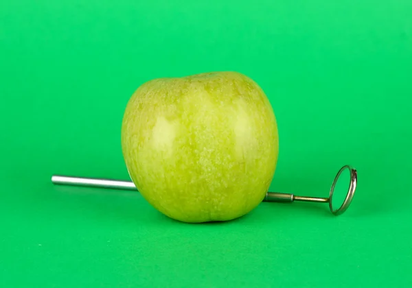 Green apple and dental tool on color background — Stock Photo, Image
