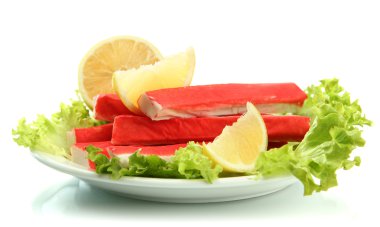 Yengeç sopalarla marul yaprakları ve plaka üzerinde beyaz izole limon