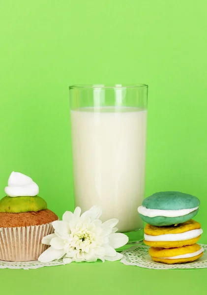 Vaso de leche fresca nueva con pasteles sobre fondo verde — Foto de Stock