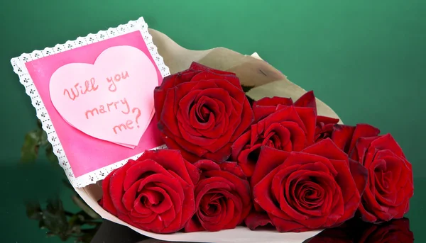 Beautiful bouquet of red roses with valentine on green background — Stock Photo, Image