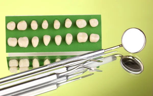 Set de herramientas dentales con dentadura postiza sobre fondo verde —  Fotos de Stock