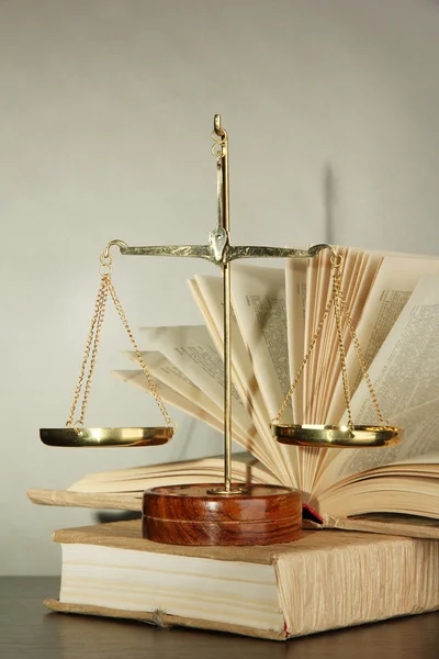 Gouden schalen van Justitie en boeken over de grijze achtergrond — Stockfoto