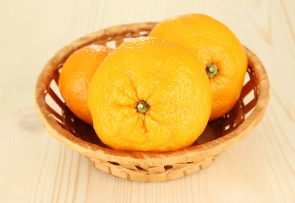 Tasty mandarines in wicker basket on wooden background — Stock Photo, Image