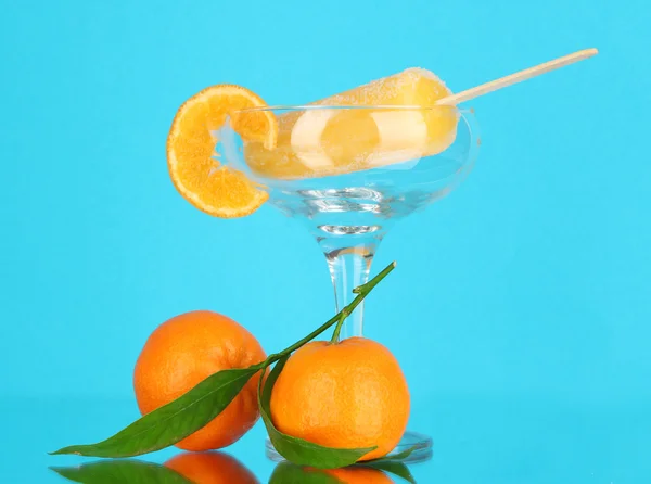 Gelbes Fruchtsaft-Eis in der Vase auf blauem Hintergrund — Stockfoto