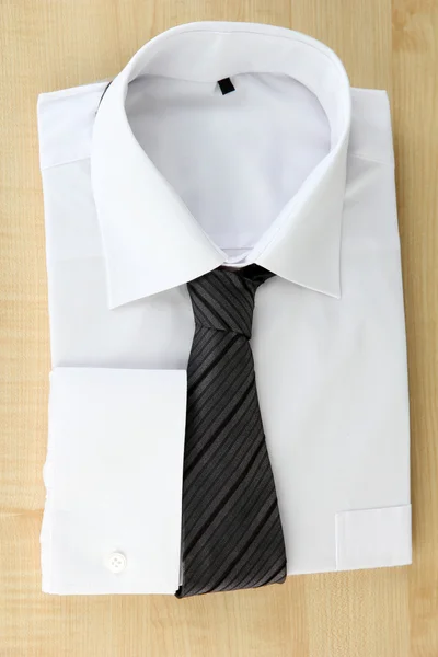 New white man 's shirt with color tie on wooden background — стоковое фото