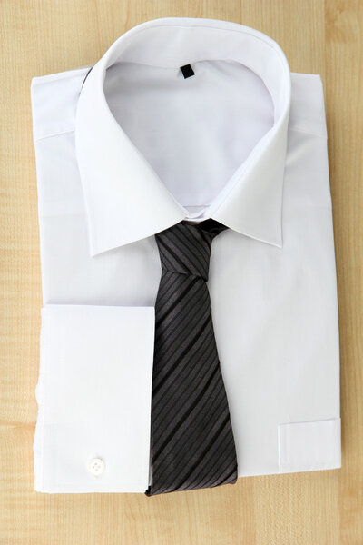 New white man's shirt with color tie on wooden background