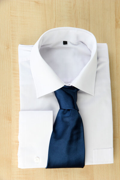 New white man's shirt with color tie on wooden background