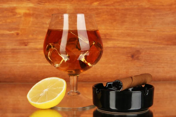 Glas Brandy mit Eis und Zitrone auf Holzgrund — Stockfoto
