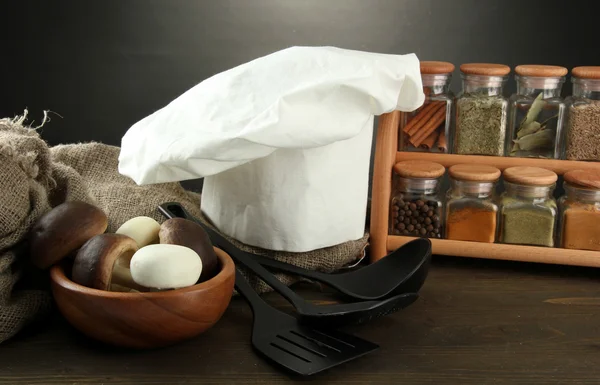 Composición con sombrero de chef y ropa de cocina sobre mesa sobre fondo gris —  Fotos de Stock