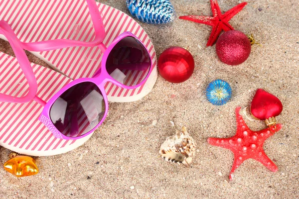 Weihnachtskugeln, Muscheln und Strandaccessoires auf Sand, Nahaufnahme — Stockfoto