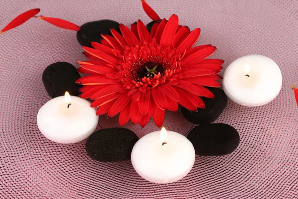 Piedras de spa con flores y velas en agua en el plato —  Fotos de Stock