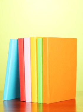yeşil zemin üzerine çok renkli kitap yığını