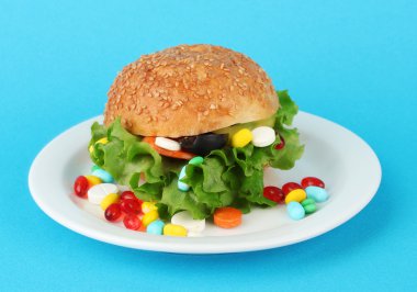 Conceptual image for nutritional care:assorted vitamins and nutritional supplements in bun.On color background clipart