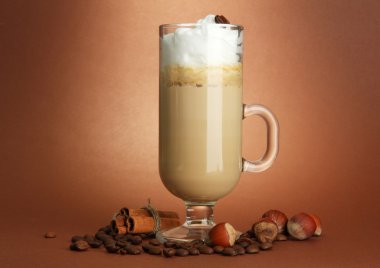 Fragrant coffee latte in glass cup with spices, on brown background clipart