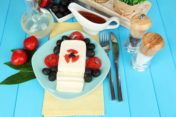 Feta cheese on plate decorated with spices and oil on blue wooden table close-up — Stock Photo, Image