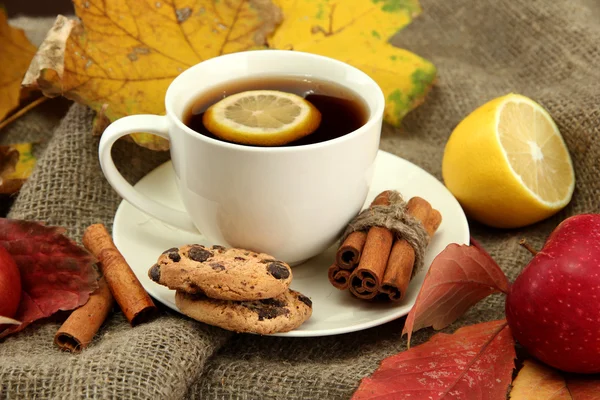 Tasse de thé chaud et feuilles d'automne, sur fond de toile de jute — Photo