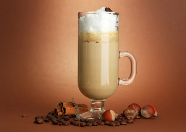 Café con leche fragante en taza de vidrio con especias, sobre fondo marrón —  Fotos de Stock