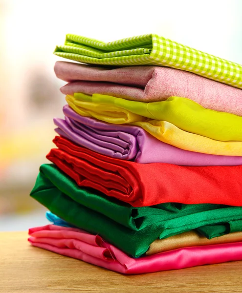 Heap of cloth fabrics on wooden table — Stock Photo, Image