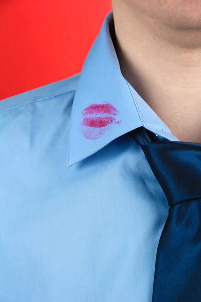 Lipstick kiss op de kraag van het shirt van de mens, op rode achtergrond — Stockfoto