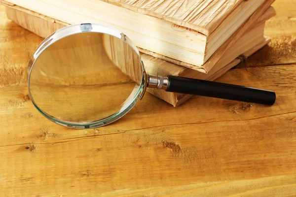 Magnifying glass and books on table — Stock Photo, Image