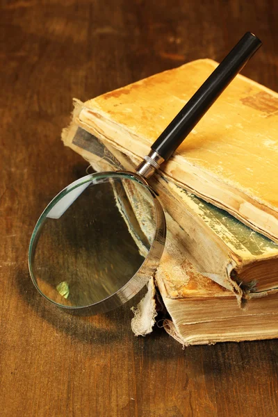 Magnifying glass and books on table — Stock Photo, Image