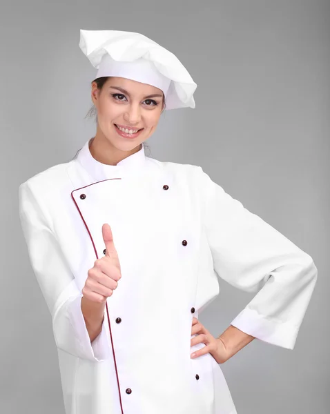 Portrait of young woman chef on grey background — Stock Photo, Image