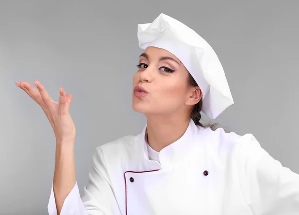 Portrait of young woman chef on grey background — Stock Photo, Image