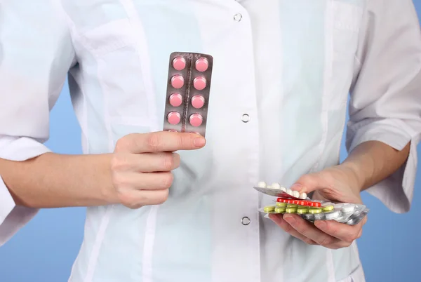 Primer plano de las píldoras de la mano del médico femenino, sobre fondo de color —  Fotos de Stock