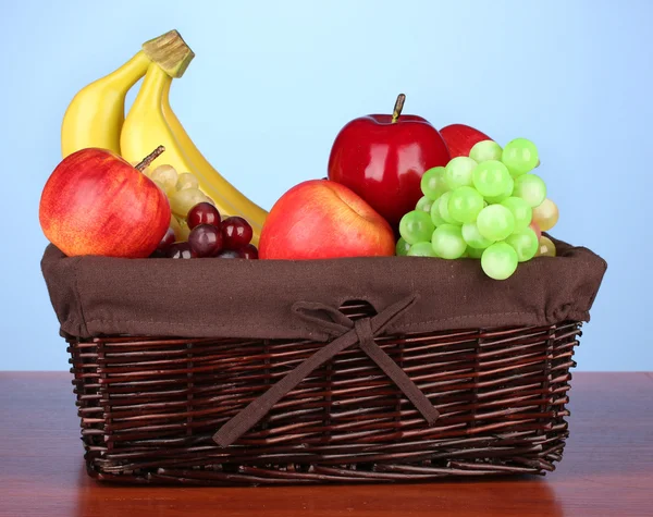 Cesta de vime com frutas no fundo de cor — Fotografia de Stock