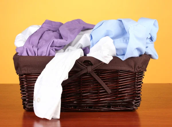 Яркая одежда в корзине для белья, на цветном фоне — стоковое фото