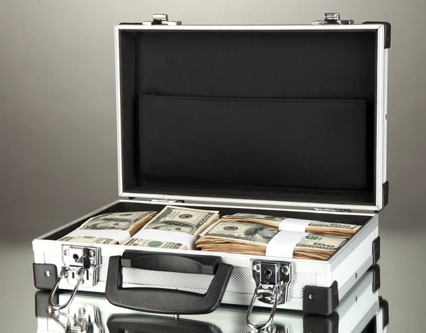 Suitcase with 100 dollar bills on grey background — Stock Photo, Image