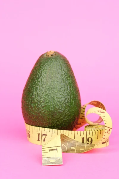 Avocado con metro su fondo rosa — Foto Stock