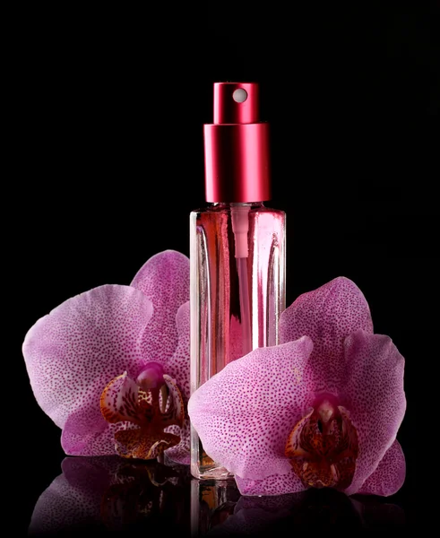 Frauenparfüm in schönen Flaschen und Orchideenblüten, auf schwarzem Hintergrund — Stockfoto