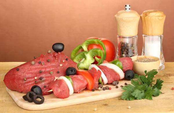 Raw beef meat marinated with herbs and spices on wooden table on brown background — Stock Photo, Image