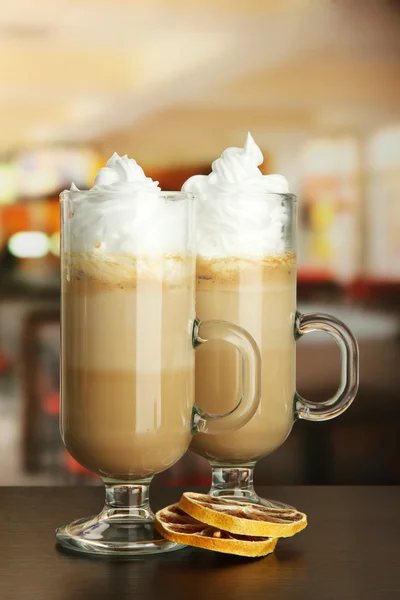 Caffè caffelatte fragrante in tazze di occhiali con arancione secco, su tavolo in caffè — Foto Stock