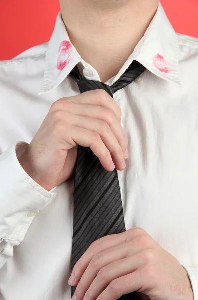 Lipstick kiss op de kraag van het shirt van de mens, op rode achtergrond — Stockfoto
